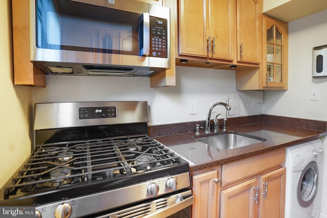 3827 Hamilton St Unit D-203, Hyattsville, MD 20781 - kitchen featuring appliances with stainless steel finishes, washer / dryer, a sink, glass insert cabinets, and dark stone counters