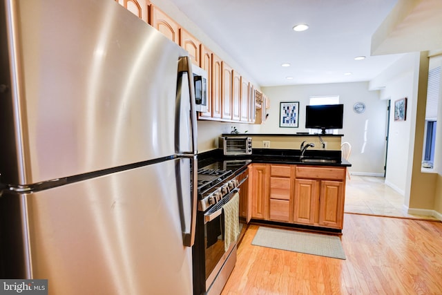 kitchen featuring kitchen peninsula, light hardwood / wood-style floors, sink, and appliances with stainless steel finishes