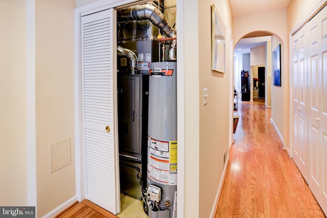 corridor featuring water heater and light hardwood / wood-style flooring