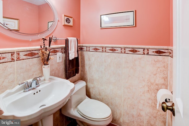 bathroom featuring toilet, tile walls, and sink