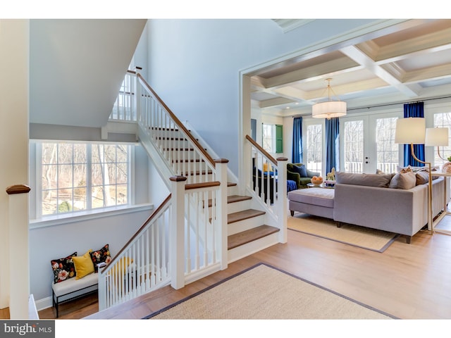 staircase featuring french doors, beamed ceiling, hardwood / wood-style flooring, and coffered ceiling