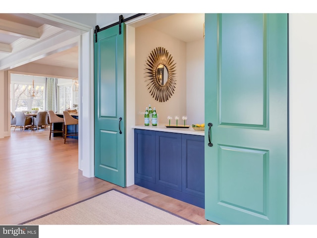 entrance foyer with an inviting chandelier, light wood-type flooring, a barn door, and beam ceiling