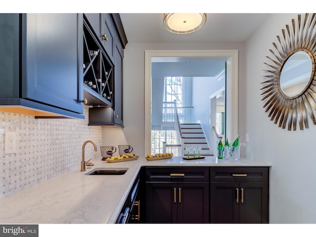 kitchen with decorative backsplash, light stone countertops, and sink