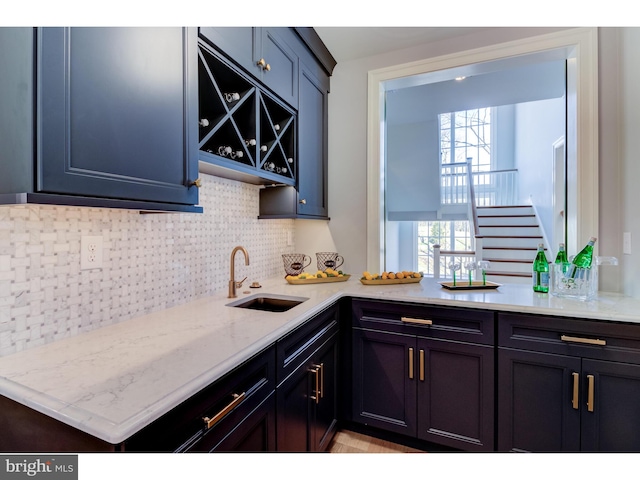 kitchen with light stone countertops, sink, and backsplash