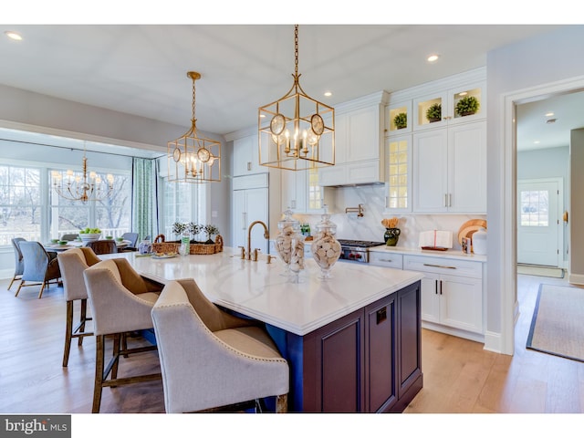 kitchen with white cabinetry, light hardwood / wood-style floors, decorative light fixtures, and a healthy amount of sunlight