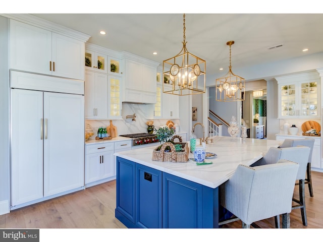 kitchen with white cabinetry, blue cabinetry, hanging light fixtures, and light wood-type flooring