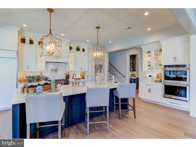 kitchen with pendant lighting, white cabinets, double oven, and a breakfast bar area