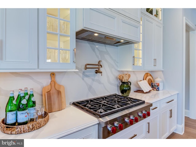 kitchen with white cabinetry, a wealth of natural light, premium range hood, and stainless steel gas cooktop