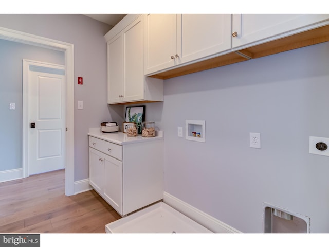 clothes washing area with cabinets, light hardwood / wood-style floors, hookup for an electric dryer, and washer hookup