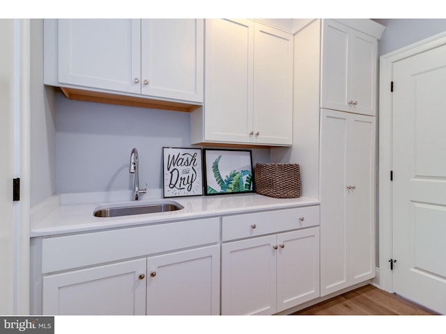 kitchen with white cabinets, light wood-type flooring, and sink