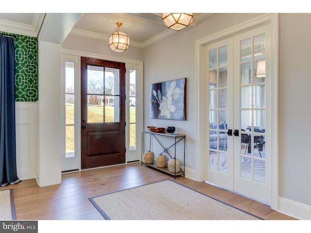 entrance foyer with crown molding, light hardwood / wood-style flooring, and french doors