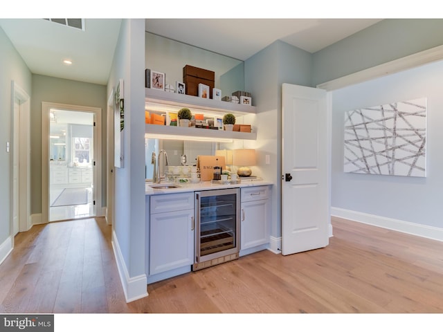 bar featuring white cabinetry, wine cooler, light wood-type flooring, and sink