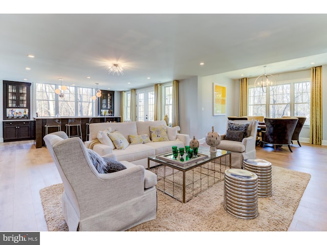 living room with light wood-type flooring and an inviting chandelier