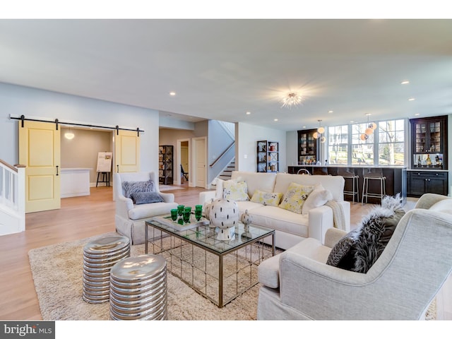 living room with a barn door and light hardwood / wood-style flooring