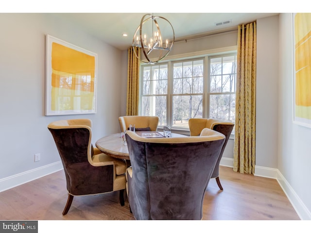 dining space featuring wood-type flooring, plenty of natural light, and a chandelier