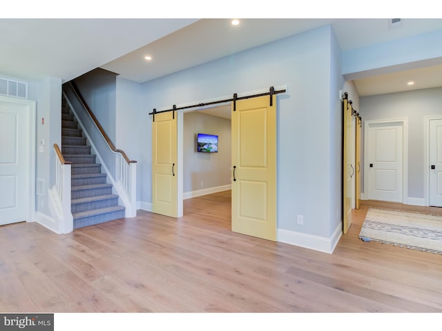 unfurnished room featuring light wood-type flooring and a barn door