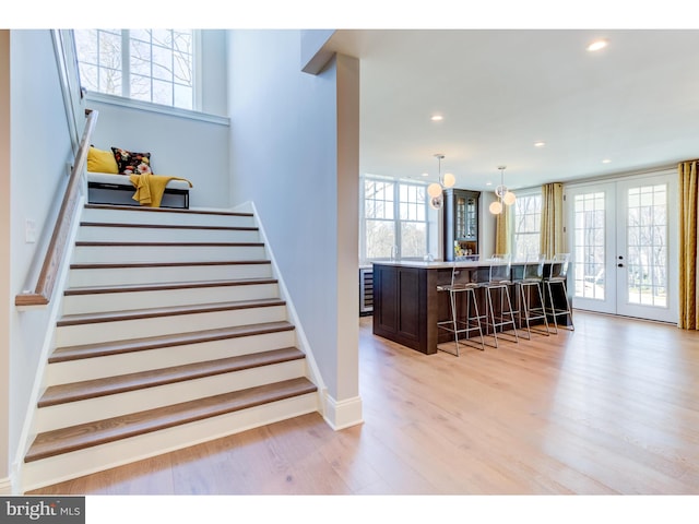 stairway with hardwood / wood-style floors, french doors, indoor bar, and plenty of natural light