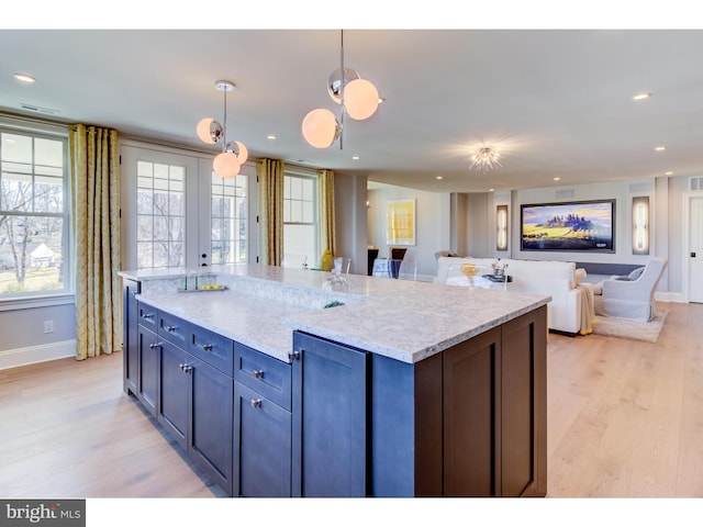 kitchen featuring french doors, light hardwood / wood-style flooring, pendant lighting, light stone countertops, and a center island