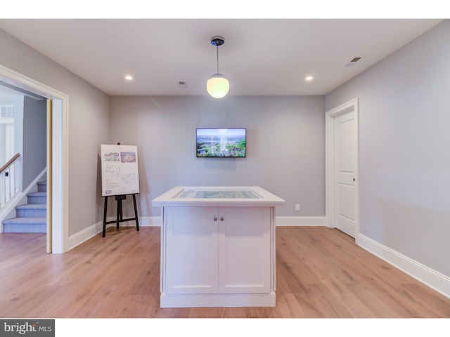 kitchen featuring a kitchen island, pendant lighting, white cabinetry, and light hardwood / wood-style floors