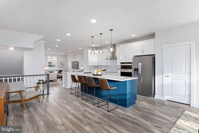 kitchen with light wood-type flooring, appliances with stainless steel finishes, decorative light fixtures, a breakfast bar, and white cabinets