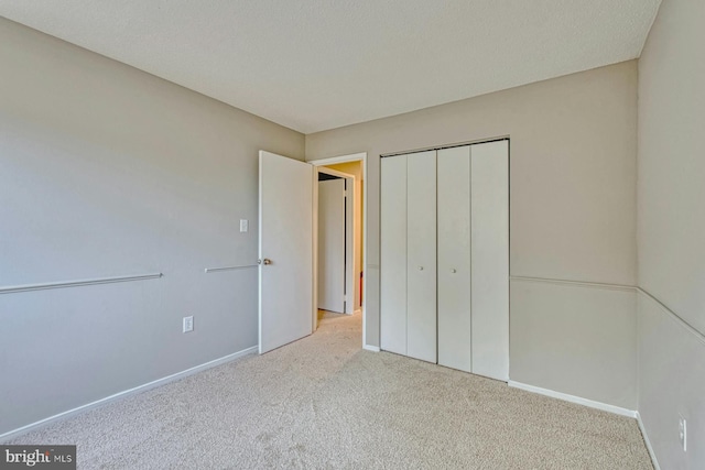 unfurnished bedroom featuring a closet, a textured ceiling, and light colored carpet