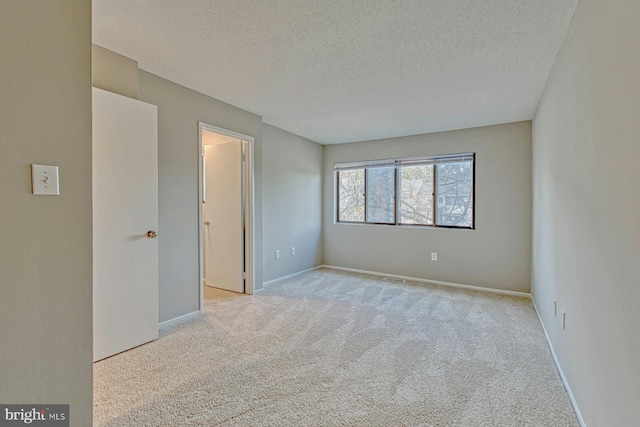 carpeted empty room with a textured ceiling