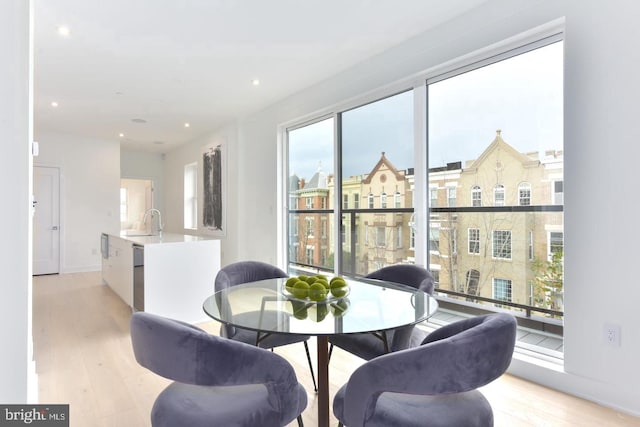 dining space featuring light wood-type flooring, sink, and plenty of natural light