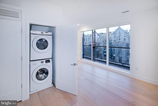 clothes washing area featuring stacked washer / drying machine and light hardwood / wood-style floors