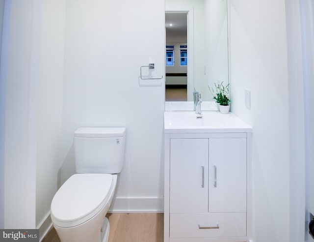 bathroom featuring toilet, vanity, and hardwood / wood-style floors