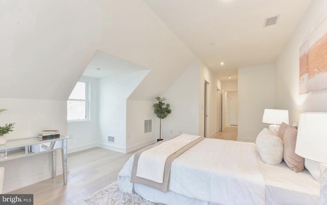 bedroom with vaulted ceiling and light hardwood / wood-style flooring