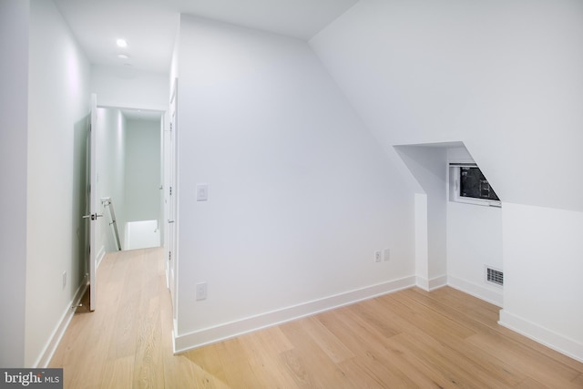 bonus room with light wood-type flooring and vaulted ceiling