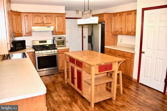 kitchen with dark hardwood / wood-style flooring, decorative light fixtures, sink, and stainless steel appliances