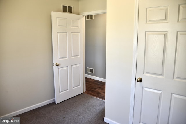 interior space featuring dark colored carpet and a closet