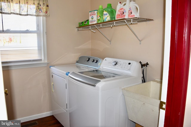 clothes washing area with dark wood-type flooring, sink, and washing machine and clothes dryer