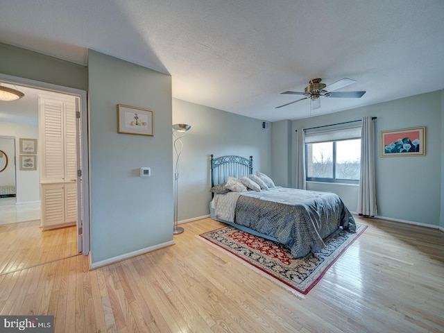 bedroom with light wood-type flooring, ceiling fan, and a textured ceiling