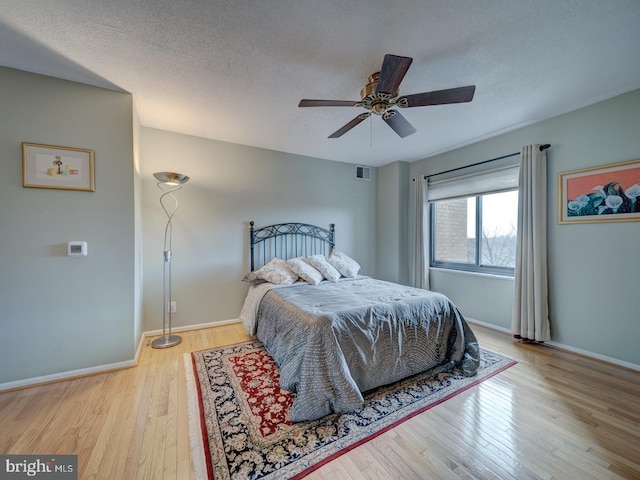 bedroom featuring a textured ceiling, ceiling fan, and light hardwood / wood-style floors