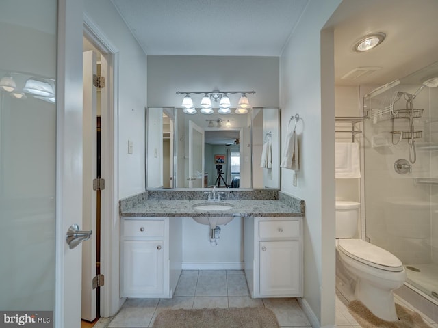 bathroom with sink, toilet, a tile shower, and tile patterned flooring