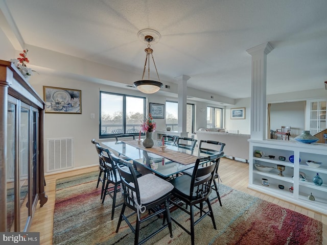 dining room featuring light hardwood / wood-style flooring and ornate columns