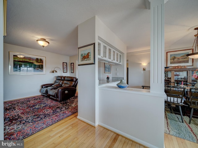 hallway with light wood-type flooring and a textured ceiling