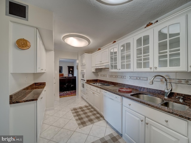 kitchen featuring sink, white appliances, dark stone countertops, and white cabinets