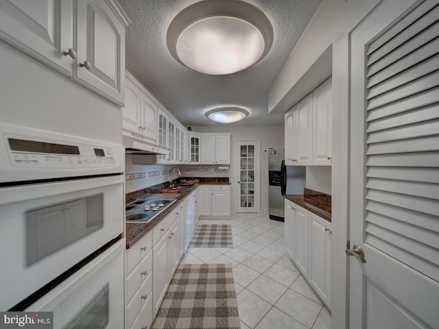 kitchen with sink, white appliances, white cabinets, and light tile patterned floors