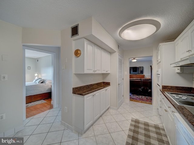 kitchen featuring white cabinetry, white appliances, dark stone countertops, and light tile patterned floors