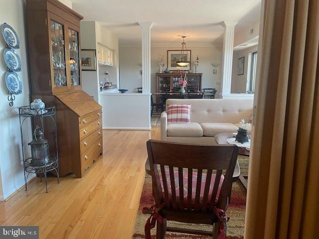 interior space featuring ornate columns, light wood-type flooring, and crown molding