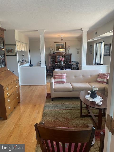 living room featuring hardwood / wood-style floors, a textured ceiling, and decorative columns