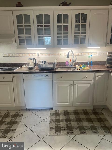 kitchen with backsplash, white dishwasher, and white cabinets