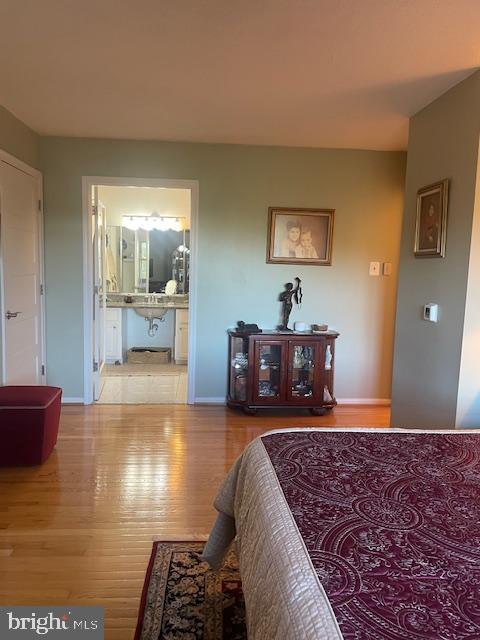 bedroom featuring ensuite bath and wood-type flooring