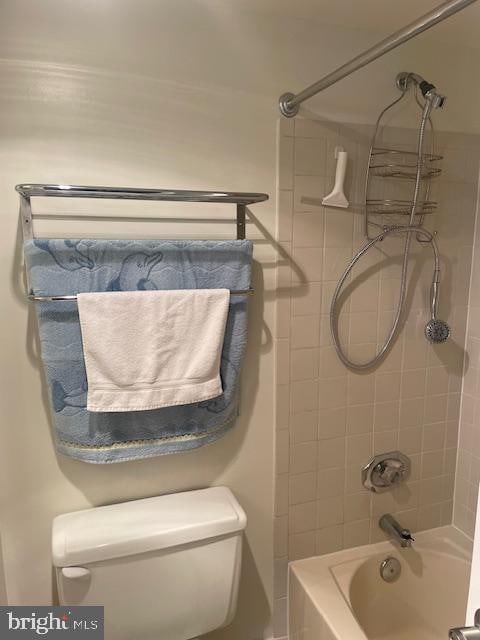 bathroom with tiled shower / bath combo and toilet