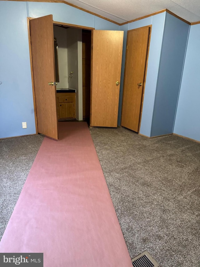 unfurnished bedroom with a textured ceiling, a closet, carpet floors, and vaulted ceiling