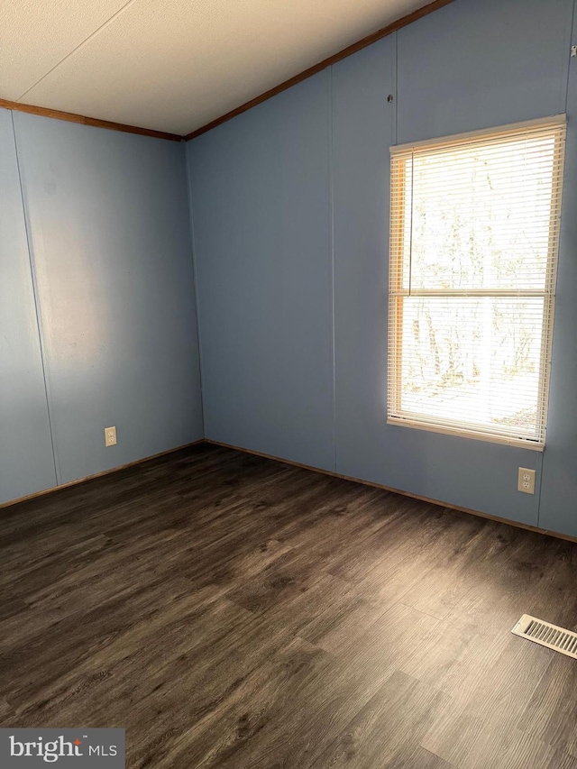 empty room featuring dark hardwood / wood-style flooring and ornamental molding