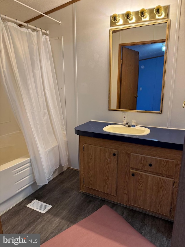 bathroom with hardwood / wood-style floors, vanity, and shower / tub combo